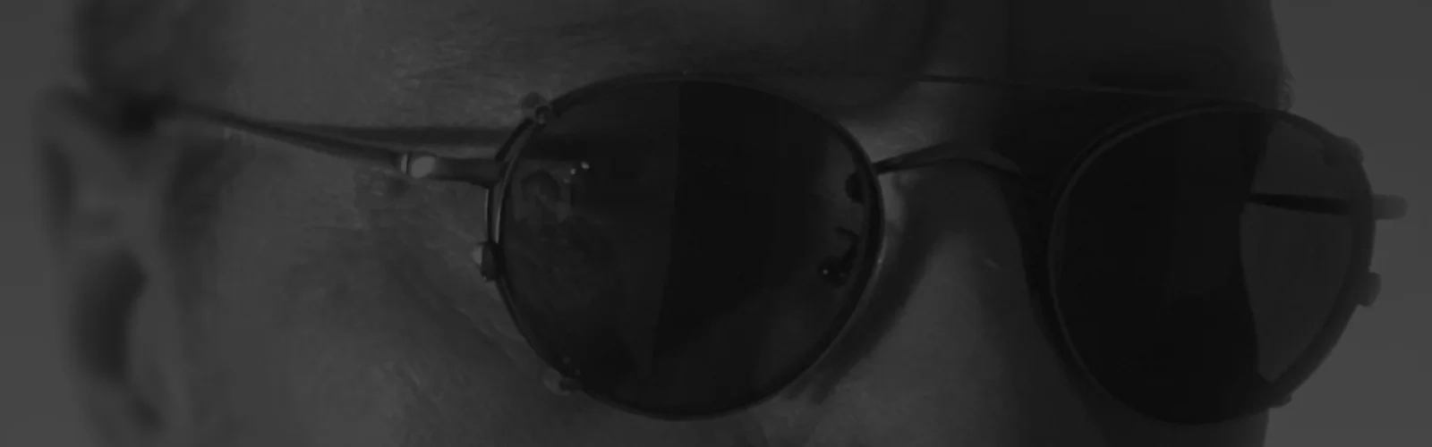 Schwarzweiß Bild von dem Autor der Webseite und dem Kopf hinter diedieseiner - Wolfram Schäfers. Das Bild zeigt lediglich seinen Augenbereich mit einer Sonnenbrille. | konzeptdesignkunst